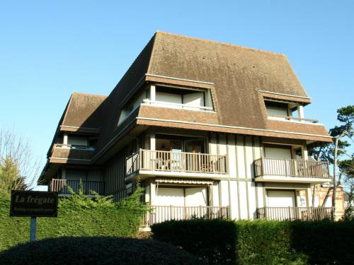 un bâtiment noir et blanc avec un toit brun dans l'établissement Grand studio en hyper-centre de Cabourg avec balcon, proche plage, parking, et prestations disponibles - FR-1-487-327, à Cabourg