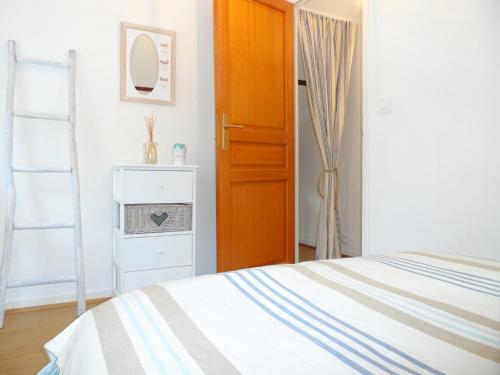 une chambre avec un lit et une porte en bois dans l'établissement Maison Cozy au Coeur de Cabourg avec Terrasse, Proche Plage, pour 4 Pers., Animaux Acceptés - FR-1-487-328, à Cabourg