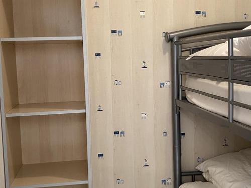 Cette chambre comprend des lits superposés et quelques étagères. dans l'établissement Cabourg : Studio Rez-de-Jardin Proche Plage, Animaux Acceptés, TV, Wi-Fi Optionnel - FR-1-487-331, à Cabourg