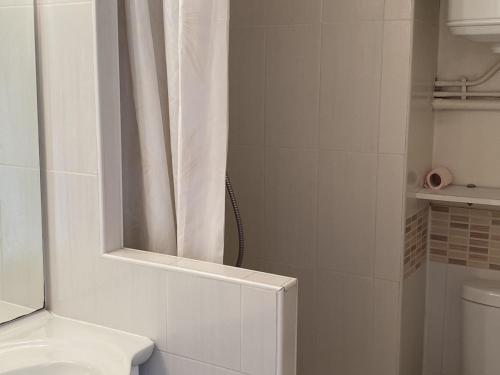 La salle de bains blanche est pourvue d'un rideau de douche et de toilettes. dans l'établissement Cabourg : Studio Rez-de-Jardin Proche Plage, Animaux Acceptés, TV, Wi-Fi Optionnel - FR-1-487-331, à Cabourg