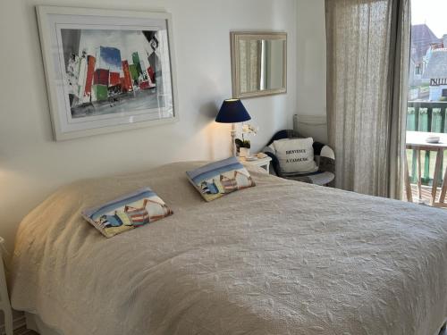 une chambre avec un lit avec deux oreillers dessus dans l'établissement Appartement 2 pièces avec balcon proche centre-ville - FR-1-487-334, à Cabourg