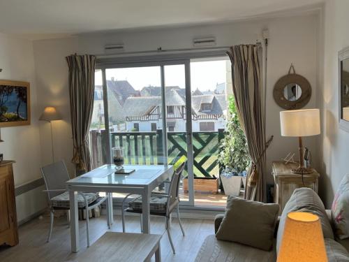 d'un salon avec une table et un balcon. dans l'établissement Appartement 2 pièces avec balcon proche centre-ville - FR-1-487-334, à Cabourg