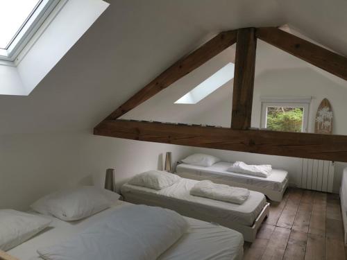 Cette chambre mansardée comprend 3 lits et une fenêtre. dans l'établissement Maison avec jardin, proche océan, 6 pers, 3 ch, animations, BBQ, parfait famille/amis - FR-1-50-81, à Mimizan