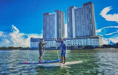 two men are on paddle boards in the water at Comfy Imperium Residence Kuantan Studio Seaview in Kuantan