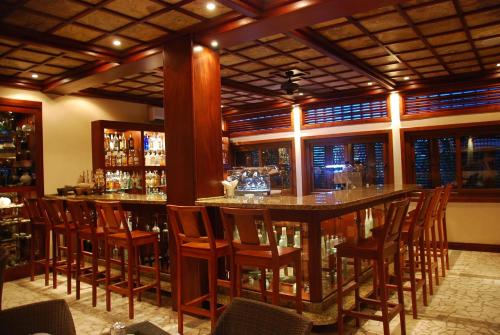 a bar with wooden chairs and a large island in a restaurant at Placencia Resort in Maya Beach