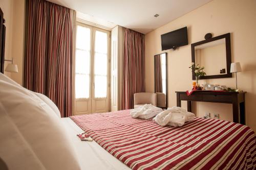a hotel room with a bed with a striped blanket at Hotel Bracara Augusta in Braga