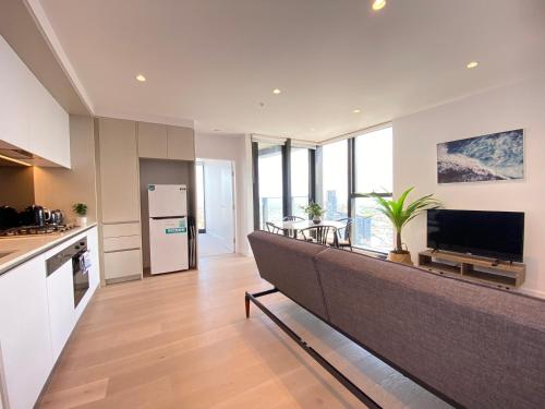 a kitchen with a large couch in the middle of a room at Rest SkyHigh Melbourne Qtr Collection in Melbourne