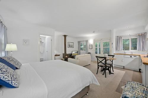a white bedroom with a large bed and a kitchen at Amelina Cottages in Marysville
