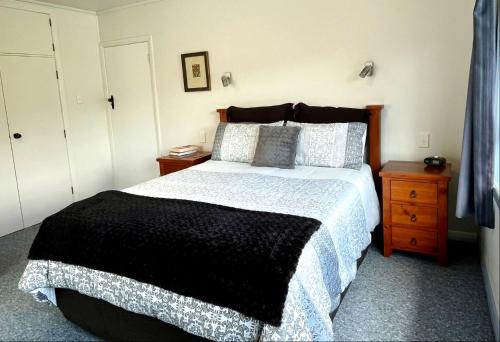 - une chambre avec un grand lit et une couverture noire et blanche dans l'établissement Salty Yarns ~ Boat Parking, à Coromandel