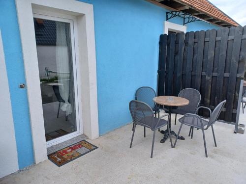 a patio with a table and chairs next to a blue wall at Aquas AP in Petrijanec