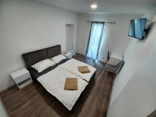 a bedroom with a bed with white sheets and wooden floors at Aquas AP in Petrijanec
