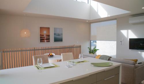 a kitchen and living room with a table and a couch at Coastal Living in Comfort in Raglan