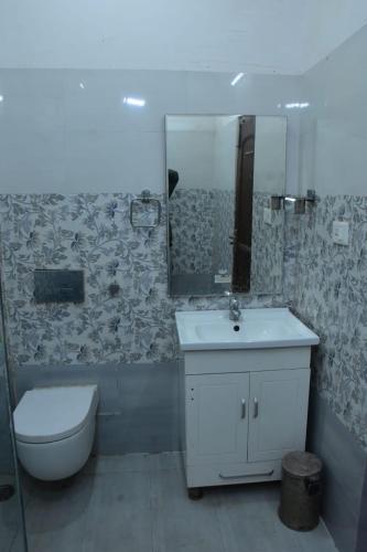 a bathroom with a sink and a toilet and a mirror at Kailash Haveli in Bikaner