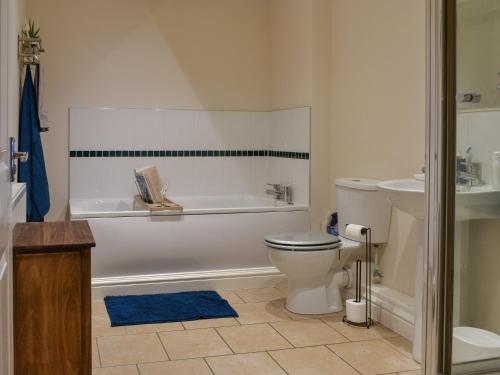 een badkamer met een bad, een toilet en een wastafel bij The Old Quaker House Apartment in Llandrindod Wells