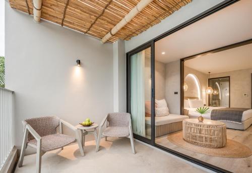 a room with a bed and two chairs and a table at VALA Hua Hin - Nu Chapter Hotels in Cha Am