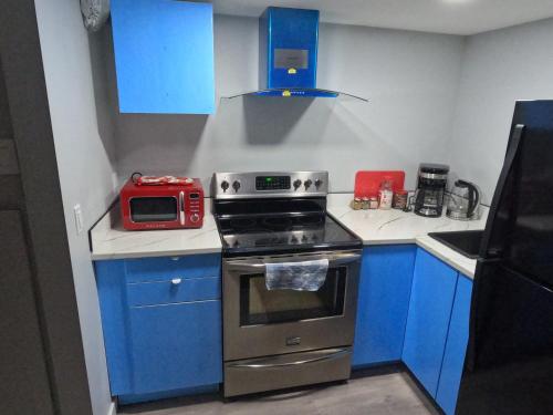 a kitchen with blue cabinets and a stove and a microwave at Gorgeous Basement Apartment in Calgary
