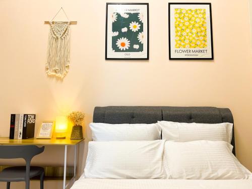 a bedroom with a bed with a table and framed pictures at Skypod Residence Puchong in Puchong