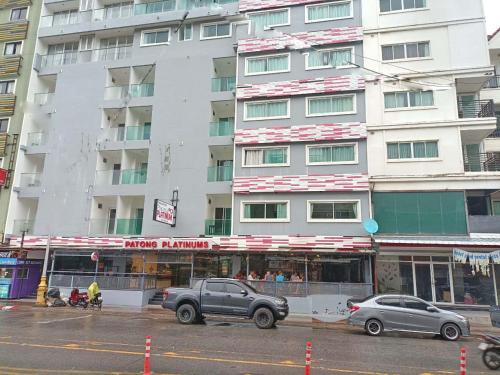 a large white building with cars parked in front of it at Patong Platinums Phuket in Patong Beach