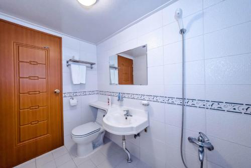 a white bathroom with a toilet and a sink at Herb in Pension in Jeju