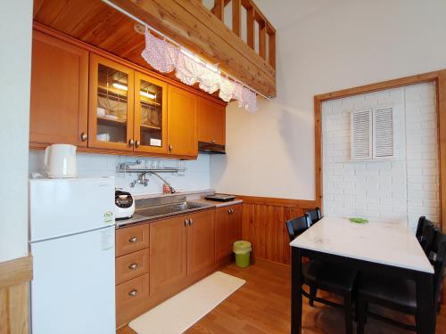 a kitchen with a white refrigerator and a table at Herb in Pension in Jeju