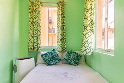 ein kleines Bett in einem grünen Zimmer mit Fenster in der Unterkunft Brew Home - 3 Bedroom House in Bacolod City