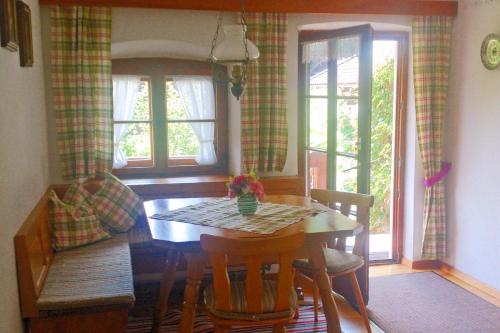 a dining room with a table and chairs and windows at Ferienwohnung Schuster am Fellerer in Aschau im Chiemgau
