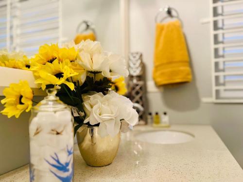 a vase with yellow and white flowers on a counter at Isle Be Back Villa in Priory