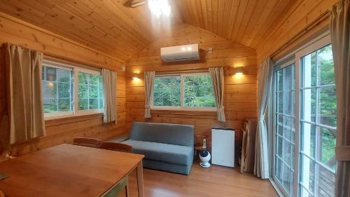 a living room with a blue couch and windows at 安曇野遊人Ｃ.Ｌ.Ｊ.クラブ in Azumino