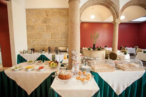 a dining room with tables with food on them at Hotel Bracara Augusta in Braga