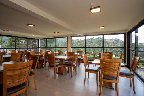 - une salle à manger avec des tables, des chaises et des fenêtres dans l'établissement Pousada Terrazzo Bonjardim, à Campos do Jordão