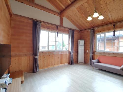 a large room with a couch and windows at Geumok Log Pension in Seogwipo