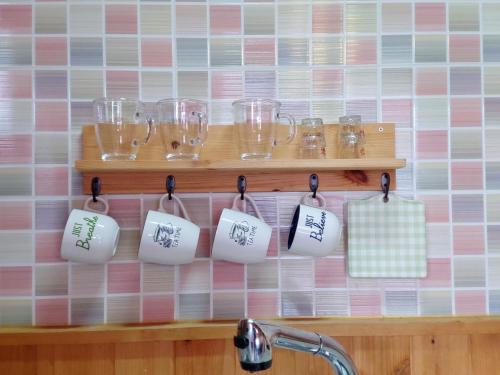 a rack of glasses and cups on a wall at Geumok Log Pension in Seogwipo