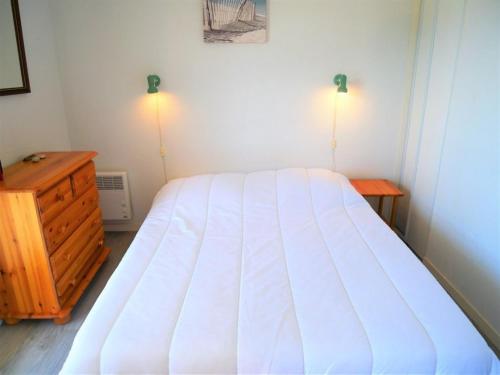 um quarto com uma cama branca e uma cómoda em madeira em Appartement Quiberon, 2 pièces, 2 personnes - FR-1-478-166 em Quiberon