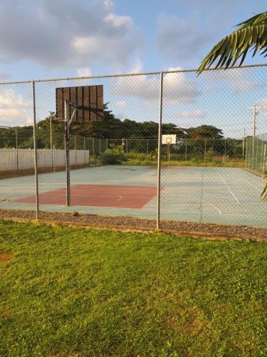 um campo de ténis com uma cerca e um cesto de basquetebol em HARMONY LA VISTA em Runaway Bay