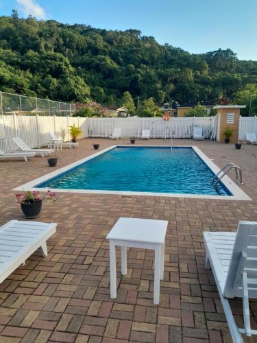 a swimming pool with two white benches in front of it at HARMONY LA VISTA in Runaway Bay