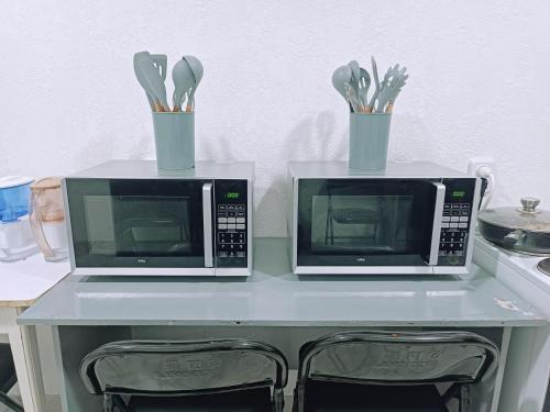 two microwaves sitting on top of a table with utensils at Nomad Inn in Bishkek