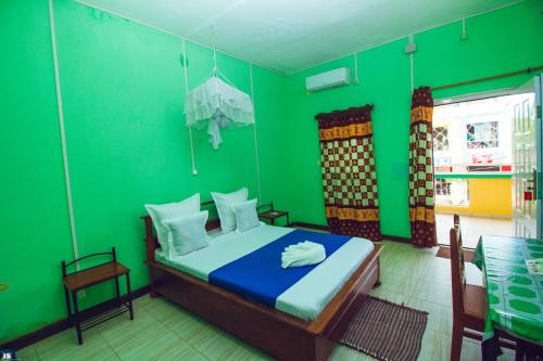 a bedroom with green walls and a bed in a room at Hotel National Ambilobe in Ambilobe