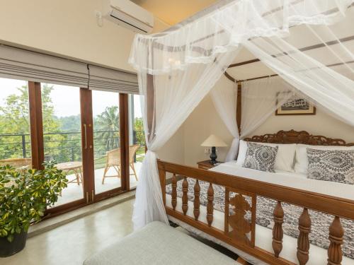 Schlafzimmer mit Himmelbett und Balkon in der Unterkunft Edgar Mansion Kandy in Kandy