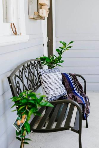 a black bench with a pillow and a plant at The Birdhouse - Your Well-deserved Country Retreat in Mudgee