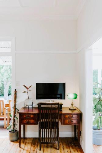 a desk with a television and a chair in a room at The Birdhouse - Your Well-deserved Country Retreat in Mudgee