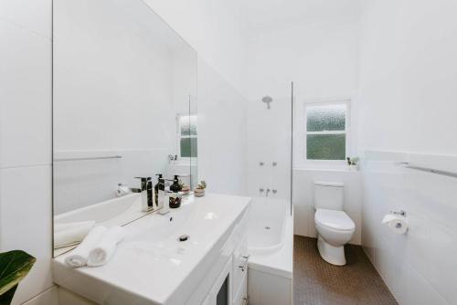 a white bathroom with a sink and a toilet at The Birdhouse - Your Well-deserved Country Retreat in Mudgee