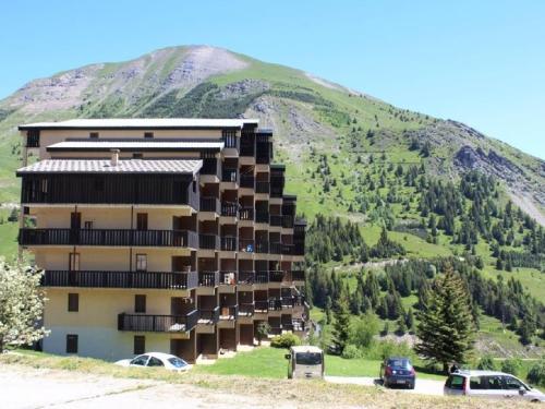 un bâtiment avec des voitures garées devant une montagne dans l'établissement Studio cabine 4 pers, pieds des pistes, proche commerces, balcon, vue sur montagnes - FR-1-297-30, à Auris