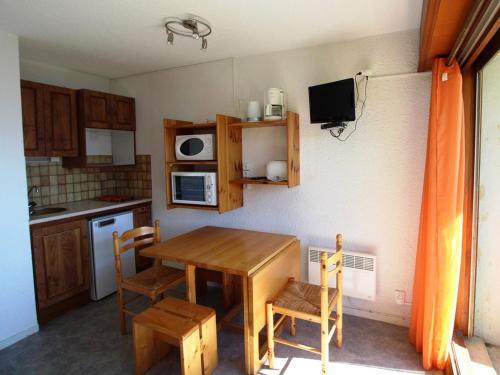 une petite cuisine avec une table et des chaises en bois dans l'établissement Studio cabine 3 pers. aux pieds des pistes avec balcon à Auris en Oisans - FR-1-297-35, à Auris