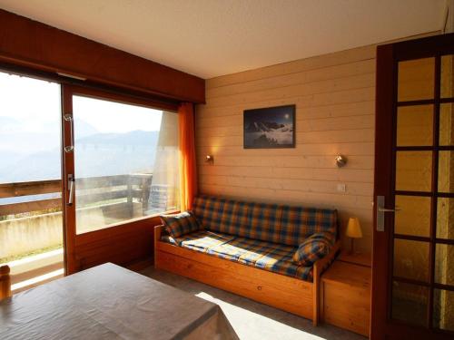 Cette chambre dispose d'un canapé et d'une grande fenêtre. dans l'établissement Studio cabine 3 pers. aux pieds des pistes avec balcon à Auris en Oisans - FR-1-297-35, à Auris