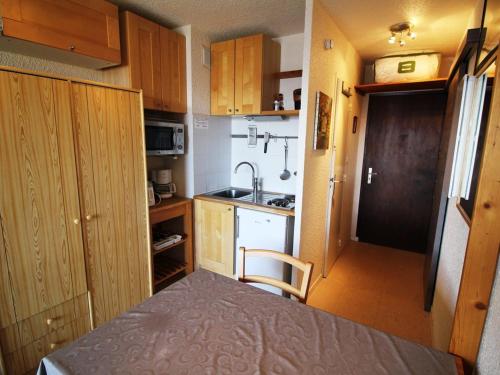 a small kitchen with wooden cabinets and a sink at Appartement Auris, 2 pièces, 3 personnes - FR-1-297-51 in Auris