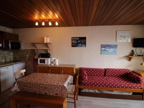 un salon avec un canapé rouge et une table dans l'établissement Studio cabine rénové au pied des pistes, balcon, parking – Auris en Oisans - FR-1-297-68, à Auris