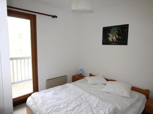 Un dormitorio con una cama blanca con una ventana. en Auris en Oisans - Appartement 3 pièces cabine - 6 couchages au pied des pistes - FR-1-297-77, en Auris