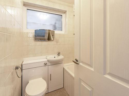 a white bathroom with a toilet and a window at Sea Vista in Bognor Regis