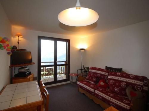 ein Wohnzimmer mit einem Sofa, einem TV und einem Fenster in der Unterkunft Appartement Auris, 2 pièces, 4 personnes - FR-1-297-161 in Auris