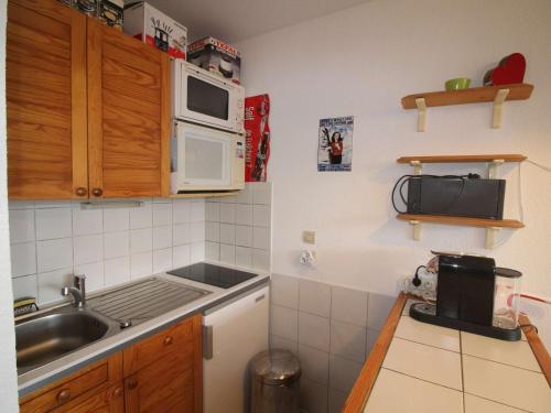 une petite cuisine avec un évier et un micro-ondes dans l'établissement Appartement 2 Pièces avec Balcon à 400m des Pistes, Parking Gratuit - FR-1-297-161, à Auris